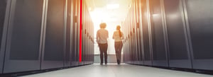 Photo of two people walking through a data center