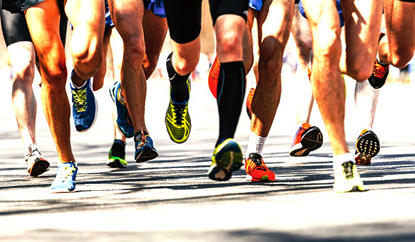 Benen en voeten van hardlopers in kleurrijke hardloopschoenen tijdens een bedrijfsloop