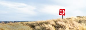 Een graslandschap met een rood symbool in de vorm van een reddingsboei – symbool voor ondersteuning en hulp door de servicedesk van DATAGROUP.