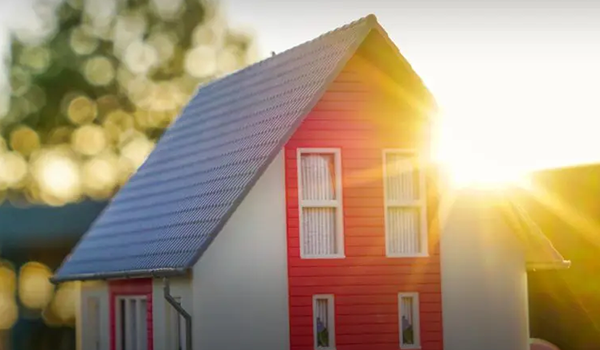 Huis met een modern rood dak tegen de achtergrond van een zonsopgang